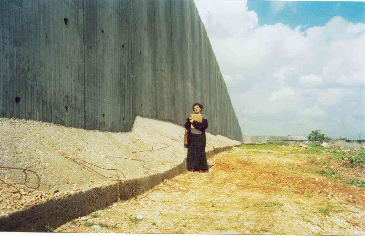 Ann Gwynne next to the wall.  The Sharon government built this wall inside the Palestinian territories to separate them from Israel and to confiscate more Palestinian lands. (Al-Jazeerah, 3/13/03). 