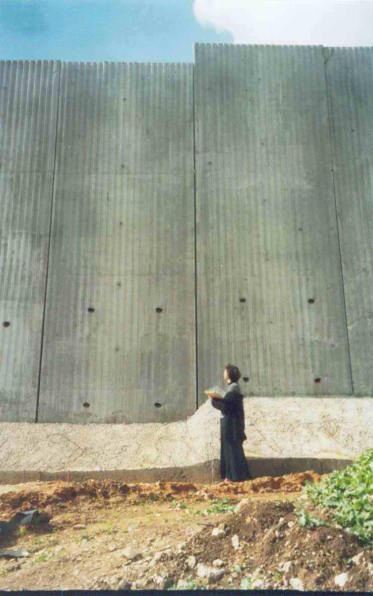 Ann Gwynne in front of the wall the Sharon government built inside the Palestinian territories to separate them from Israel and to confiscate more Palestinian lands. (Al-Jazeerah, 3/13/03). 