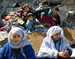 A Palestinian family on the ruins of their house which was demolished by Israeli occupation forces in Khan Younis, yesterday (An Nahar, 2/9/03). 