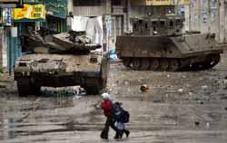 Palestinian girls passing by Israeli occupation tanks (Tishrin, 2/20/03). 