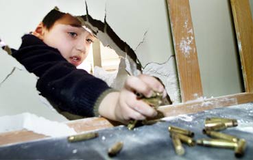 A Palestinian child trying to reach some of the bullets Israelis left behind after their raid on Balata refugee camp, Nablus, yesterday (Alqurs Alarabi, 3/18/03 
