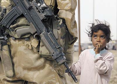 A young Iraqi girl looks up at a British soldier who is checking her father's identity papers at a checkpoint in the southern Iraqi town of Basra on Sunday (photo by ODD ANDERSEN/AFP, JT, 3/31/03).