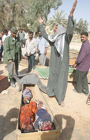 Razaq Al Kazem Al Khafaji grieves over the bodies of his children in Hilla in the southern province of Babylon on Tuesday. Khafaji lost 15 members (including six children) of his family as his car was bombed by coalition helicopters while fleeing Haidariya towards Babylon. Thirty-three civilians were killed and 310 wounded in a US-British bombing of the residential area of Nader south of the city of Hilla, 80km south of Baghdad (photo by Karim SAHIB/AFP, Jordan Times, 4/2/03).  