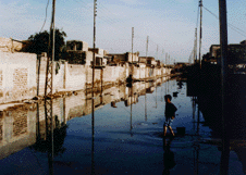 A boy wading through streets filled with raw sewage in a heil Hussein neighborhood in Basra. Sanctions prevent the importing of sweage plants spare parts. (Photo: Chuck Quilty) 