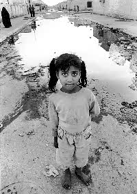 Makal district of Basrah, renamed Community of the Martyrs after heavy bombing during the Gulf War. Young girl stands in front of bomb crater (Bill Hackwell ) 